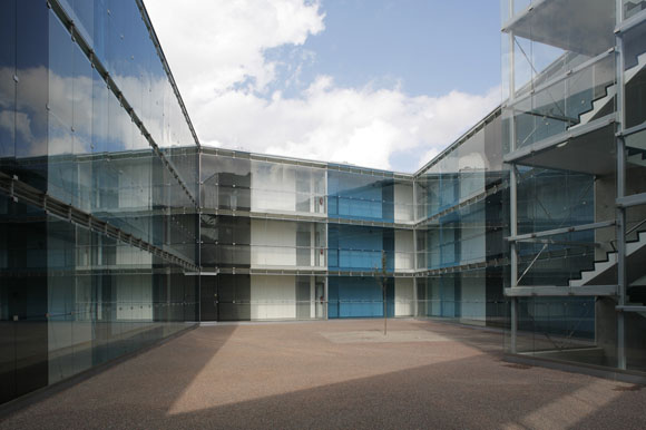 Passing through underneath the elevated corner of the BUILDING, viewers see a hidden courtyard with reflecting multicoloured glass surfaces that surround a single apple-tree growing in the courtyard.As darkness falls, the lights behind the courtyard glass walls turn on. The whole yard becomes filled with light.